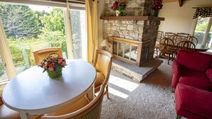 A cozy living area with a stone fireplace, a dining table with chairs, and a red sofa. - Coachlite Inn (Sister Bay)