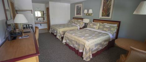Habitación de hotel con dos camas individuales, un escritorio, una silla, un ventilador de techo y un ventanal grande.