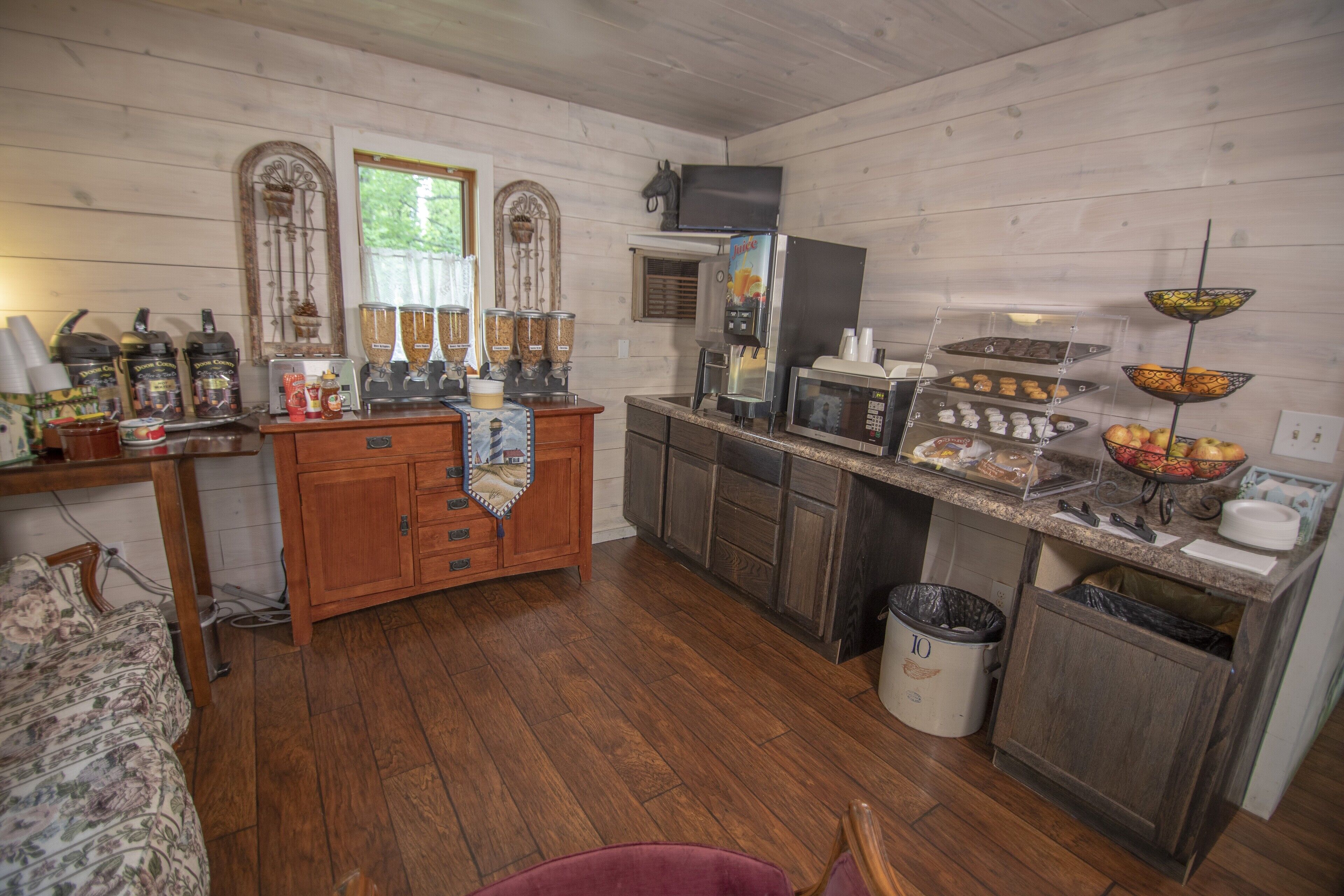 A rustic kitchen with wooden cabinets, a coffee station, and a fruit bowl.