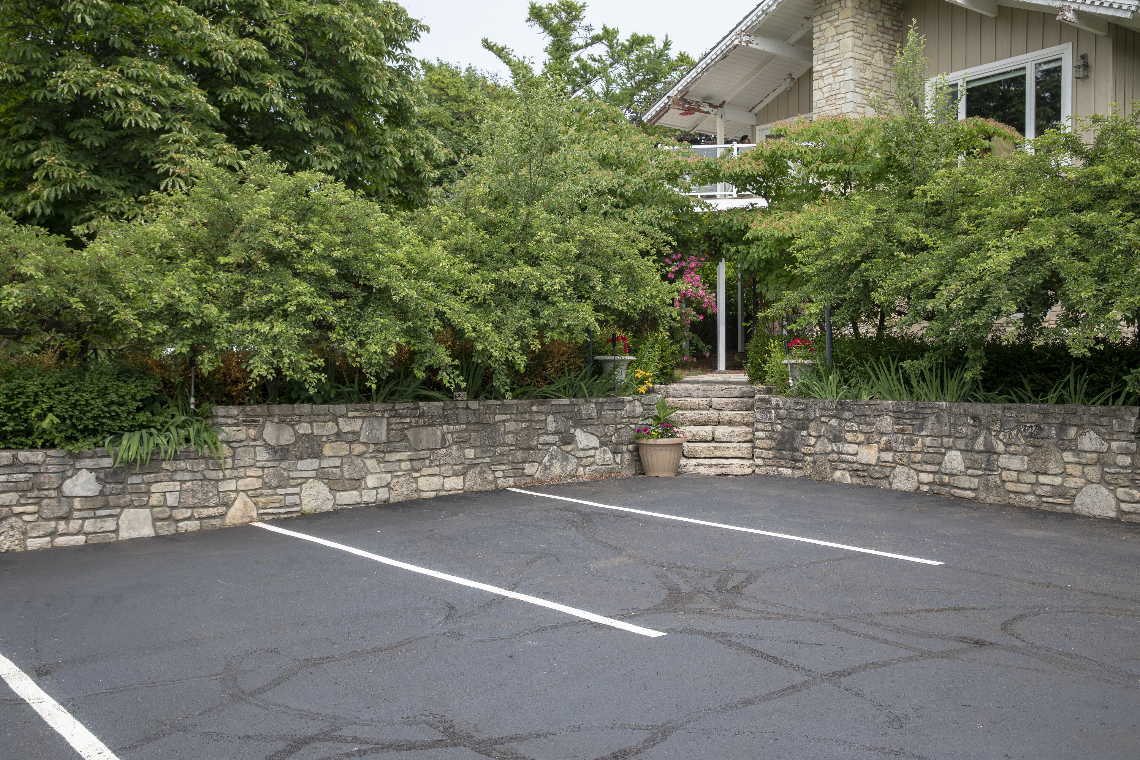 A parking area with a stone wall and greenery.