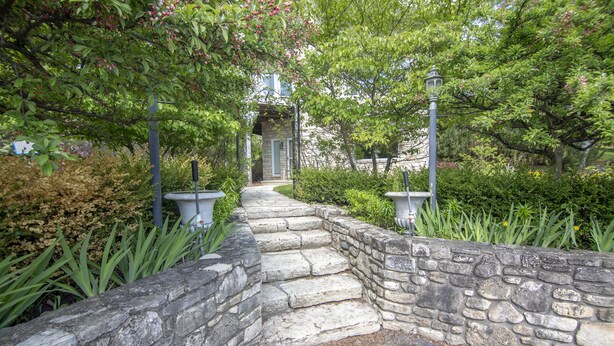 A stone pathway leading to a building entrance, surrounded by lush greenery and flowering plants. - Coachlite Inn (Sister Bay)