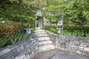 A stone pathway leading to a building entrance, surrounded by lush greenery and flowering plants. - Coachlite Inn (Sister Bay)