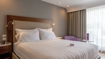 A neatly made bed with white linens, a wooden headboard, and bedside lamps.
