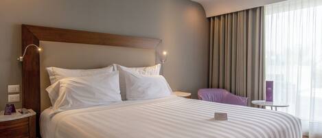 A neatly made bed with white linens, a wooden headboard, and bedside lamps.