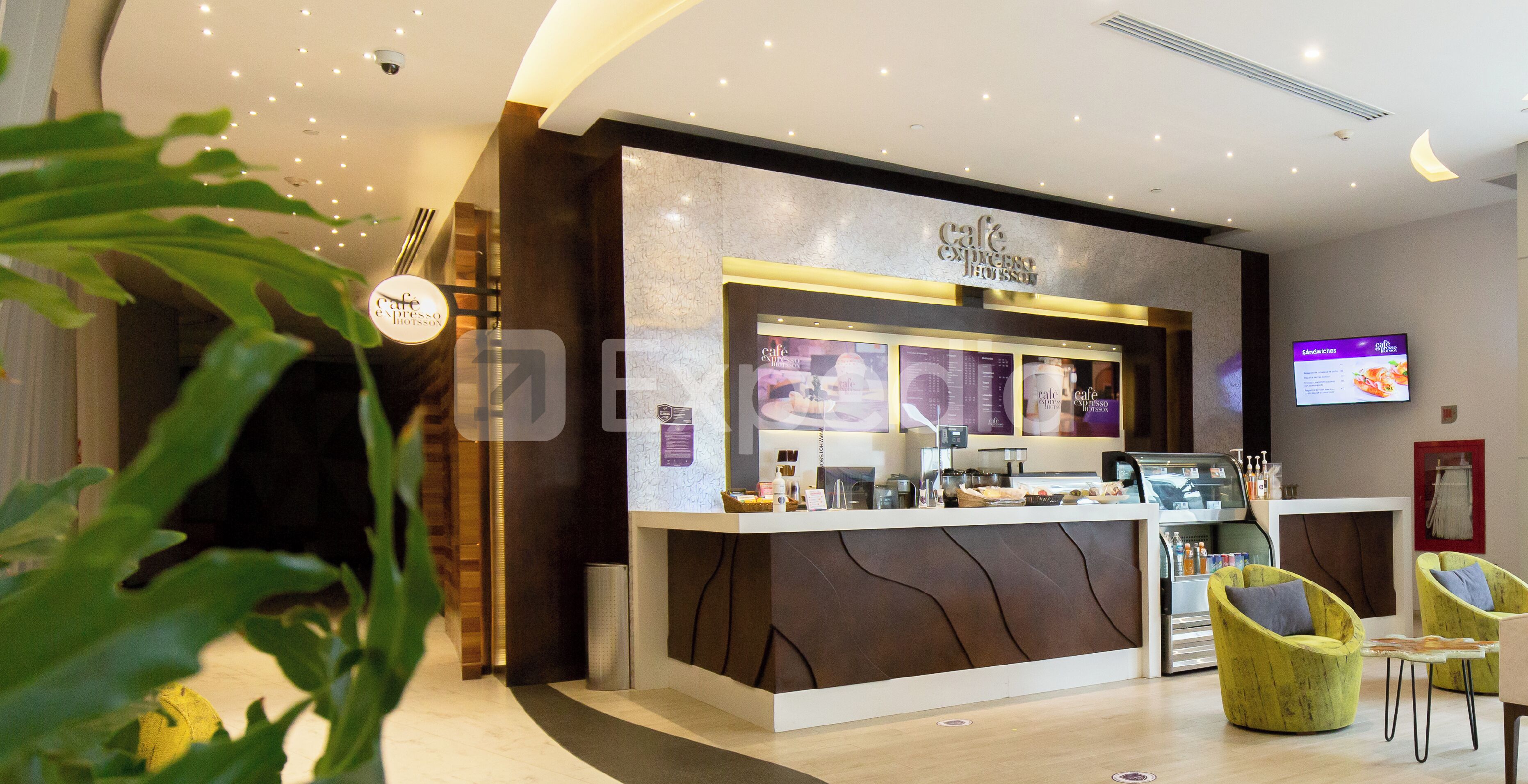 Una cafetería de diseño moderno, con un menú digital y una zona de estar con sillas.