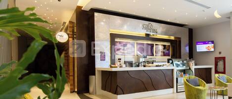 A cafe with a modern design, a digital menu board, and seating area with chairs.