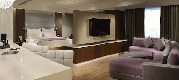 Una habitación de hotel moderna con una cama grande, un televisor, un sofá y una mesita de café.