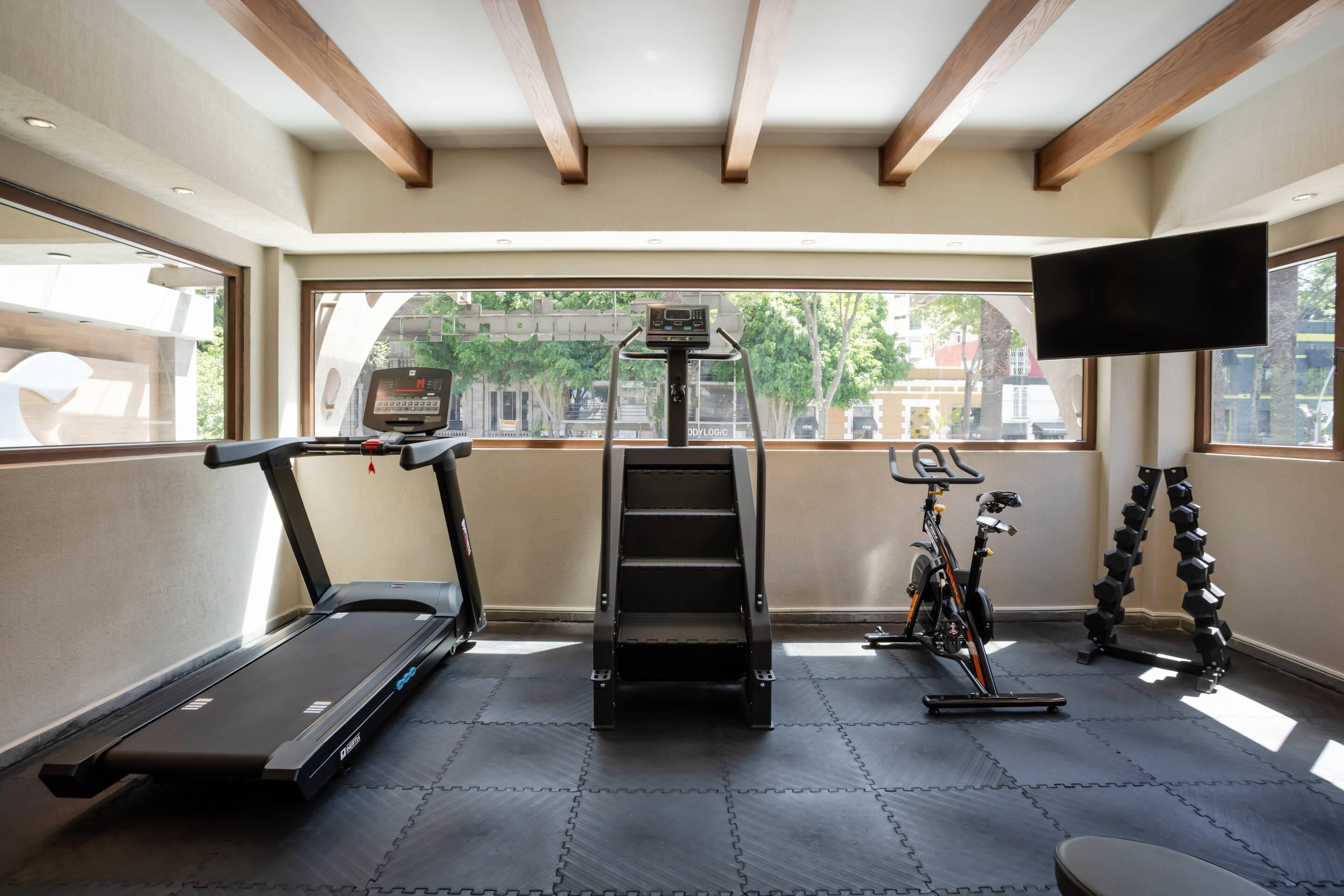 Ein Fitnessstudio mit Laufband, Steiger und Ergometer sowie Kurzhanteln.