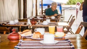 Ein Frühstückstisch für zwei Personen, gedeckt mit Geschirr, Tassen und einem Saftkrug.
