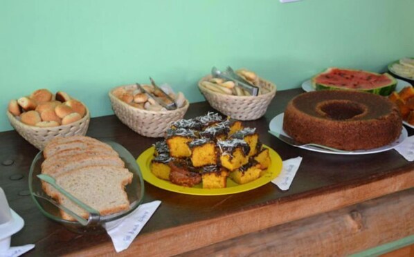 Un bufé con diversas opciones de comida, incluyendo pan, pasteles y una rebanada de sandía.