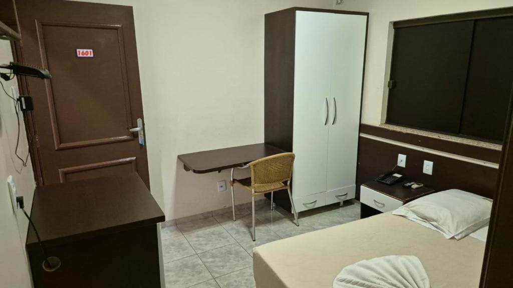 A room with a bed, a desk, a wardrobe, and a wardrobe with a mirror.