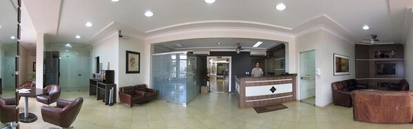 Un amplio espacio de estar con mostrador de recepción, asientos y una zona de cocina.