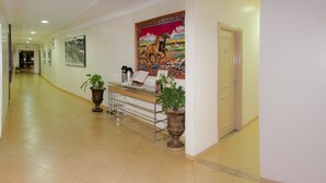 Un hall d’hôtel comprenant un comptoir d’accueil, des plantes en pot, des œuvres d’art et un sol carrelé.