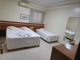 Habitación de hotel con dos camas, una mesita de noche, un espejo y una ventana con persianas.