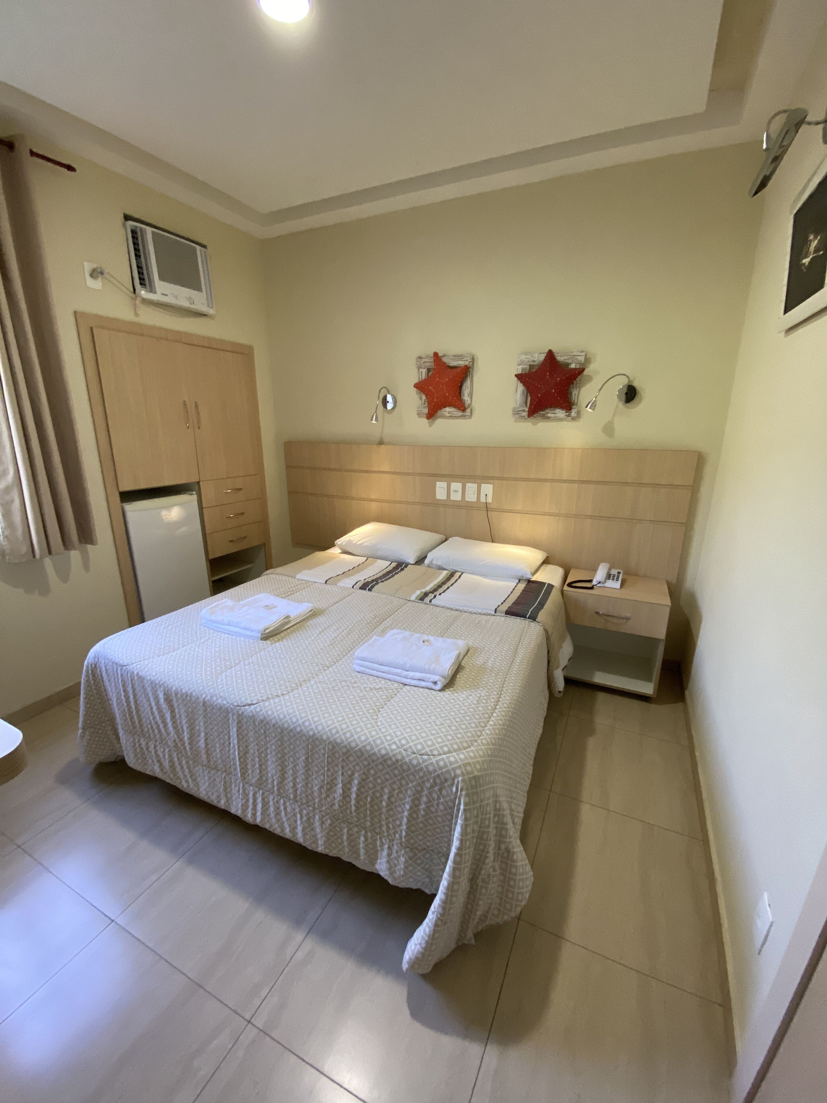 Un dormitorio con cama, mesitas de noche, armario y microondas.