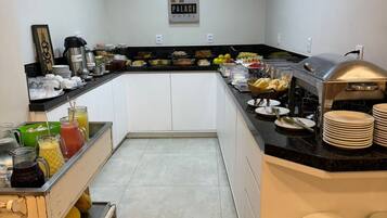 Een hotelkeuken met een buffetopstelling, inclusief een koffiehoek, fruit en diverse gerechten.