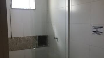 Un baño con cabina de ducha de vidrio, inodoro y ventana.