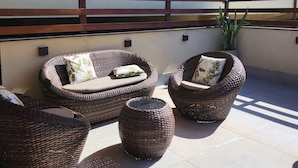 A patio with wicker furniture, a large umbrella, and a potted plant. - Palace Hotel Angra (Angra dos Reis)