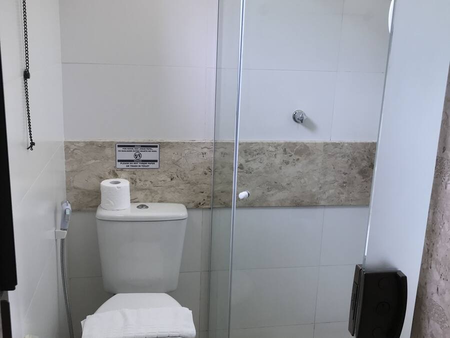 Um banheiro pequeno com vaso sanitário, box de chuveiro e uma toalha no chão.