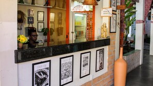 A reception area with a counter, framed artwork, a large vase, and a refrigerator stocked with beverages. - Vila Aju Pousada Temática (Aracaju)