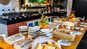 A buffet setup with various food items, plates, and utensils. - Vila Aju Pousada Temática (Aracaju)