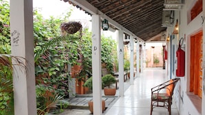 A covered outdoor corridor with potted plants, a wooden bench, and a tiled floor. - Vila Aju Pousada Temática (Aracaju)