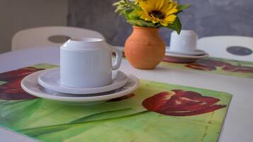 Una taza y platillo blancos sobre una mesa con un mantel individual estampado con flores.