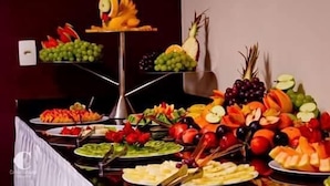 Une table de buffet où sont présentés divers fruits et légumes, disposés sur un présentoir.