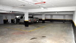 Un parking intérieur avec un sol en béton, des lignes de marquage jaune et des murs blancs.