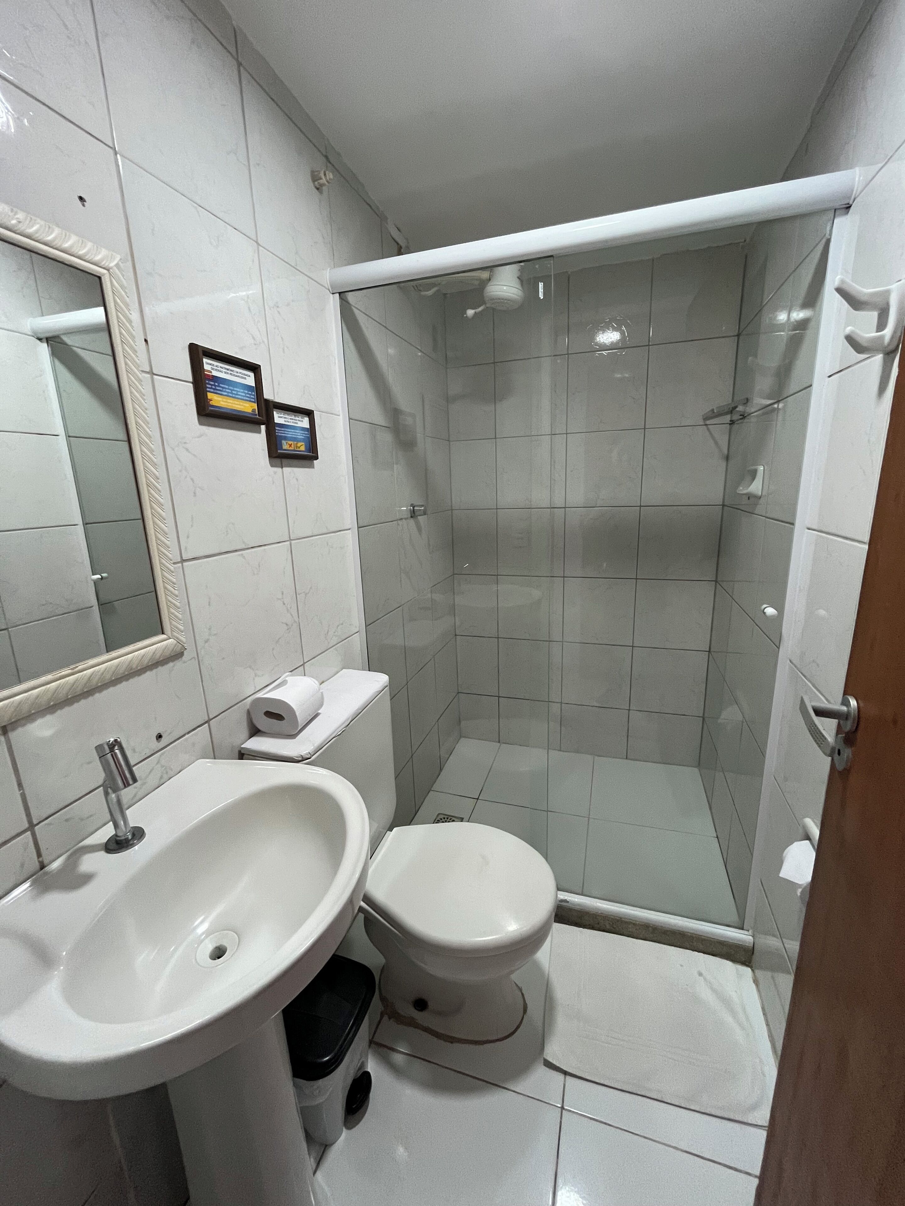 Et badeværelse med vask, toilet og brusekabine med glasvægge.