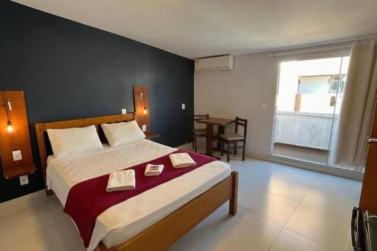A bedroom with a bed, bedside tables, a desk, and a chair.