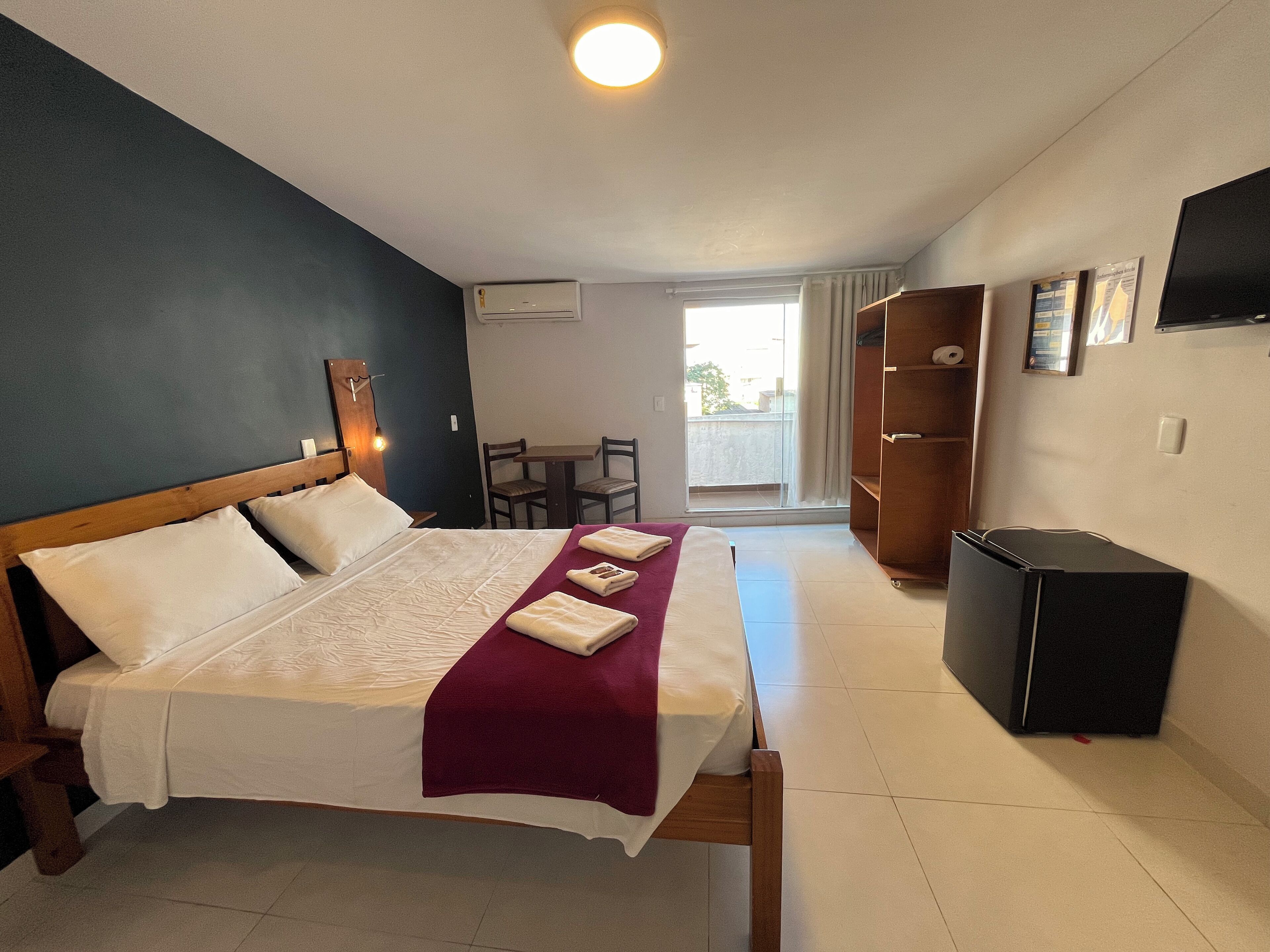 Ein Hotelzimmer mit Bett, Schreibtisch, Stuhl, Fernseher und Kleiderschrank.