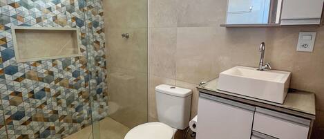 A bathroom with a shower, toilet, sink, and a mirror.