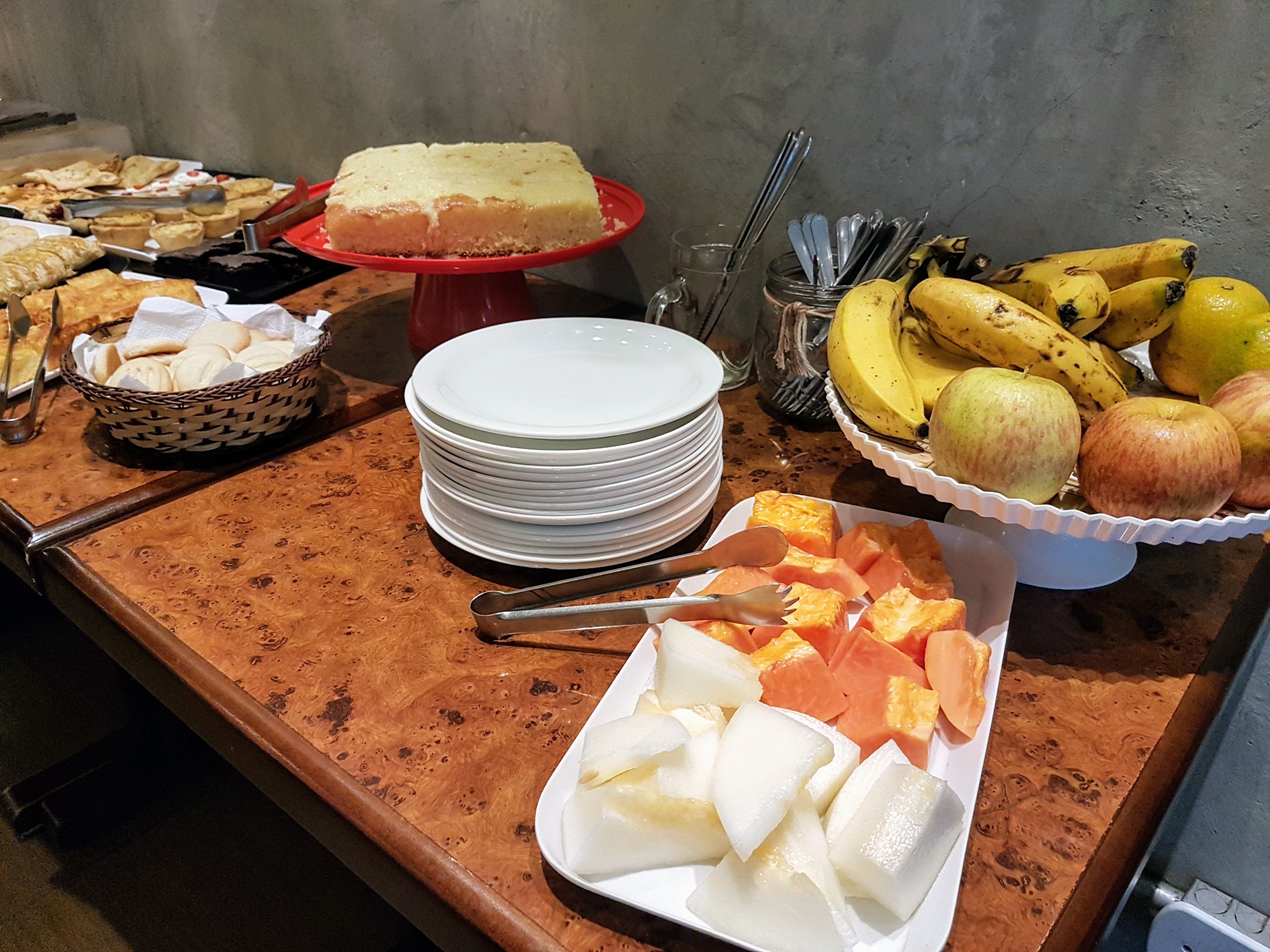 A buffet table with various food items including a cake, fruits, and a bowl of cookies.