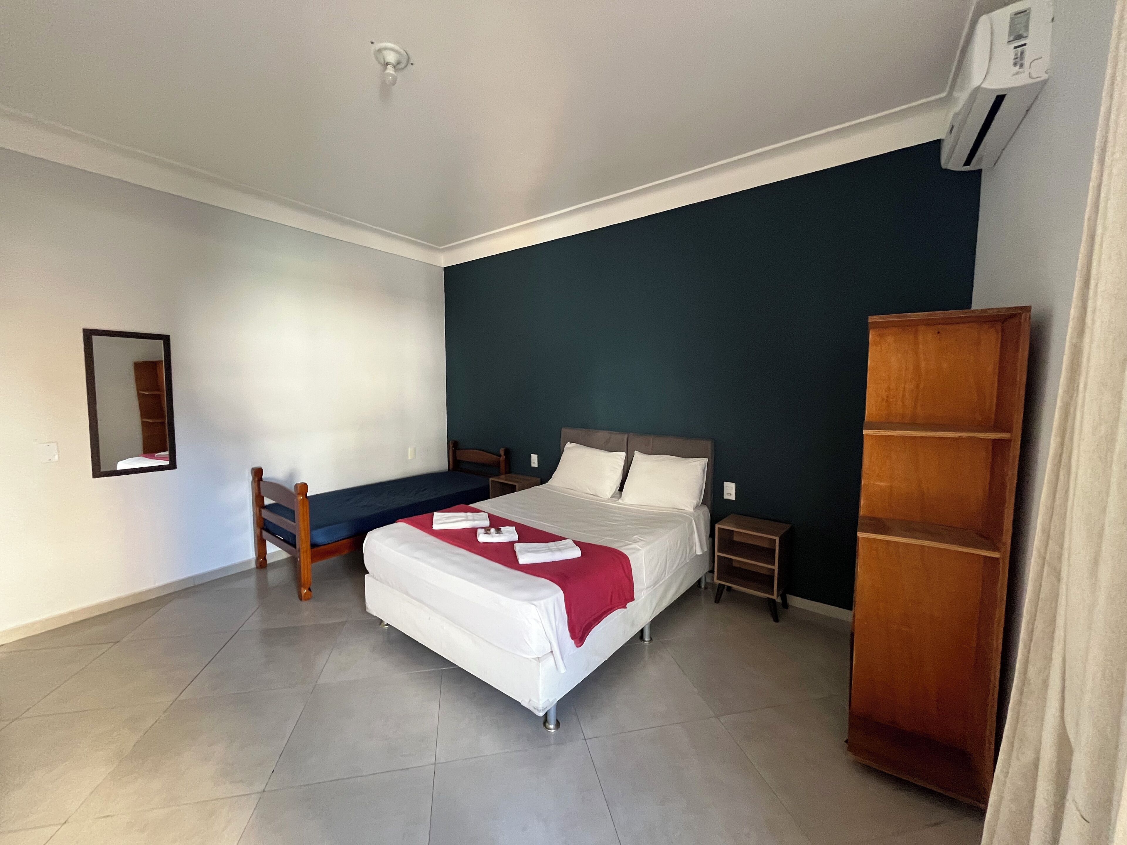 Ein Schlafzimmer mit Bett, Nachttisch, Spiegel, Kleiderschrank und Deckenventilator.