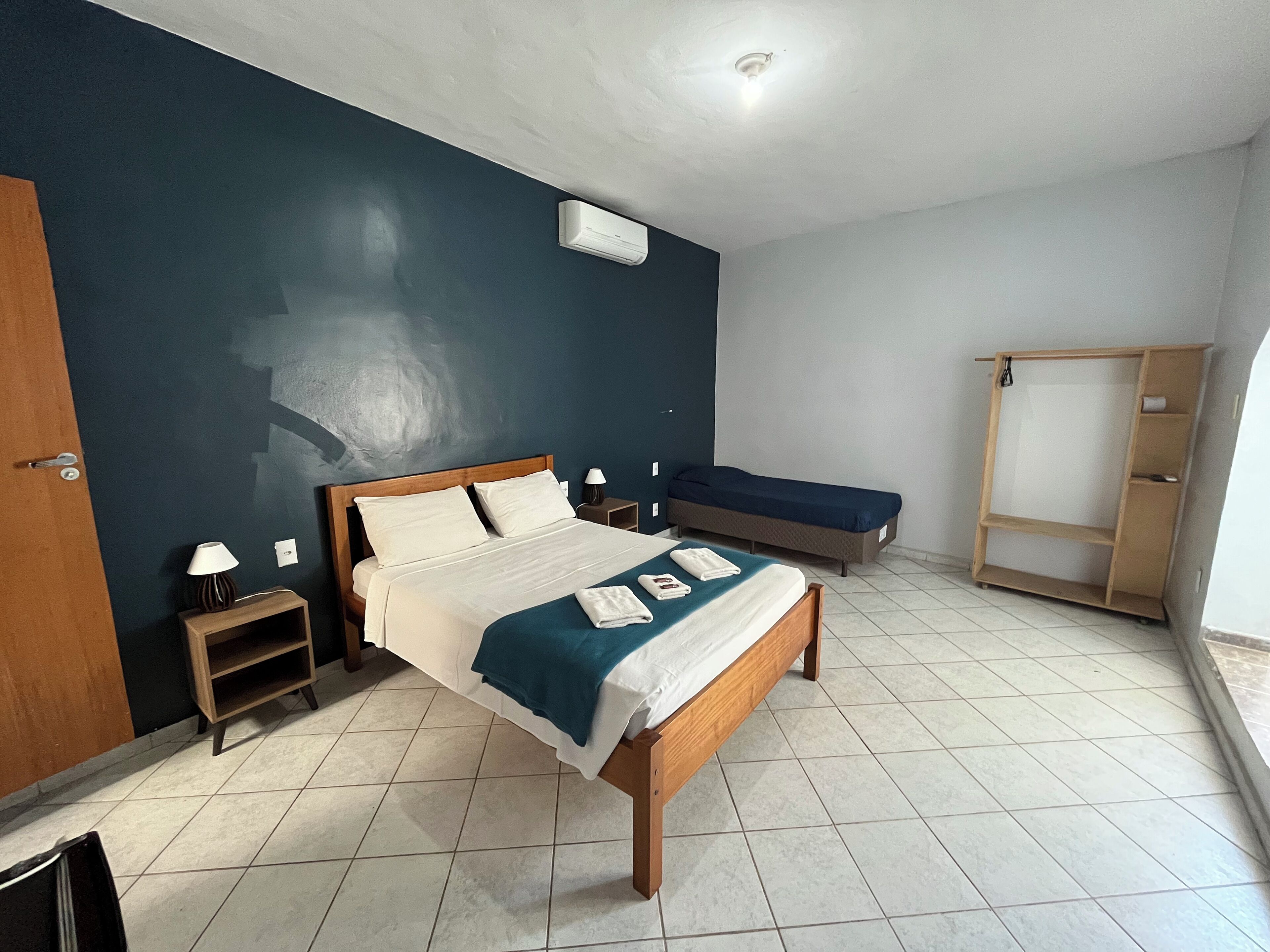 A bedroom with a large bed, a smaller bed, a wardrobe, and a bedside table with a lamp.
