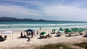 Een strand met mensen, parasols en een tent.