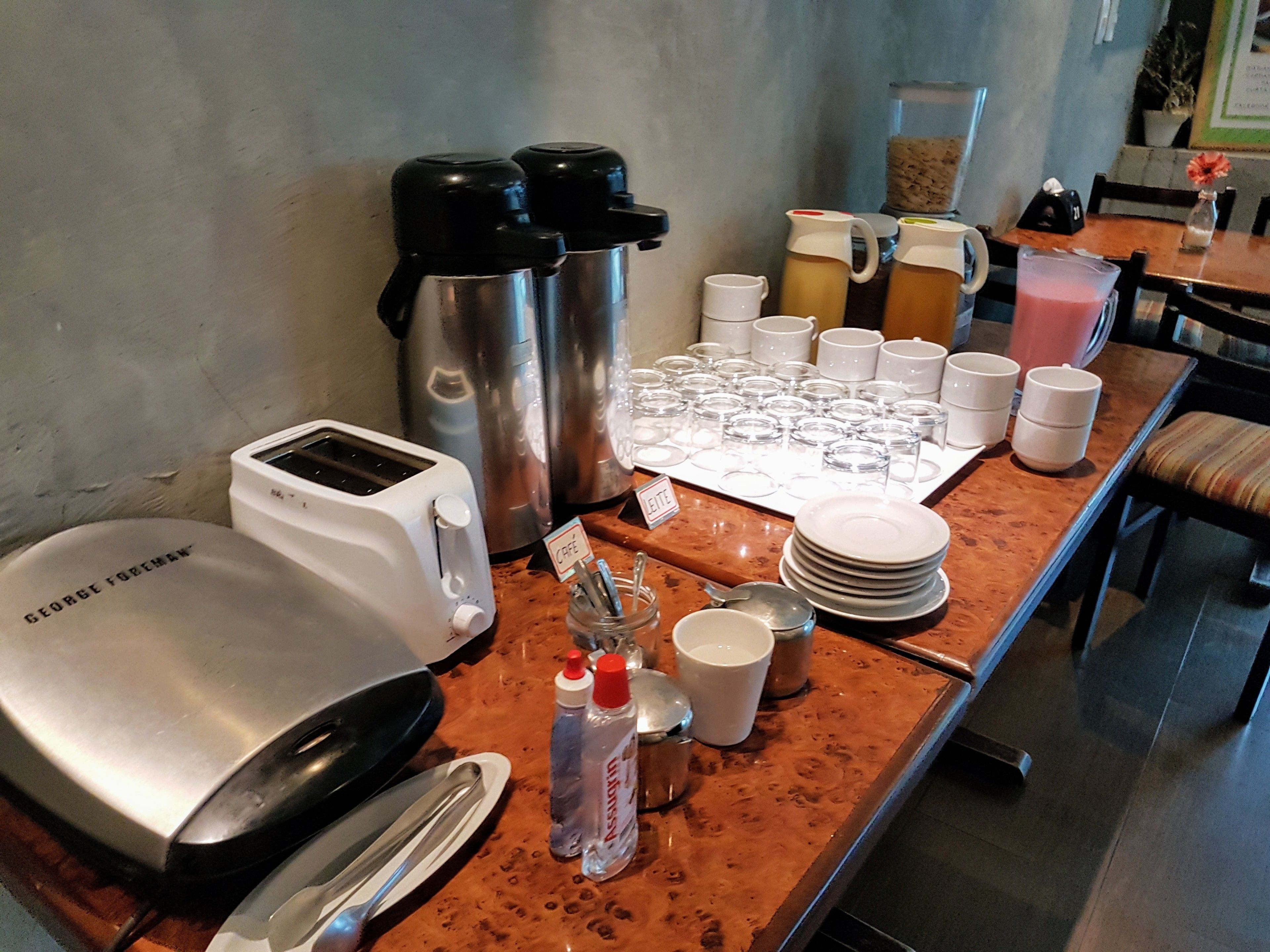 A breakfast bar with a toaster, coffee makers, and a variety of cups and plates.