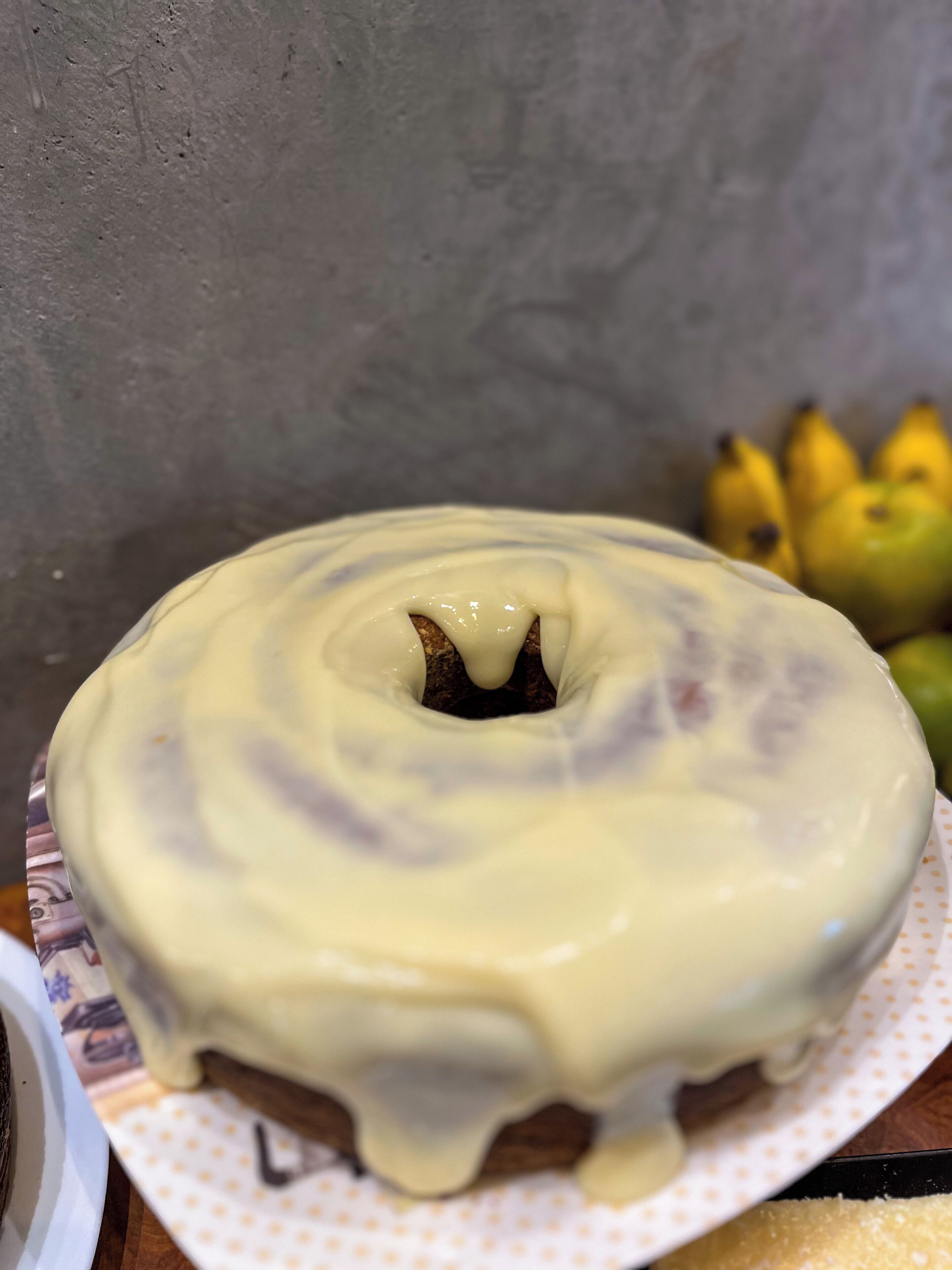 A bundt cake with a creamy glaze on a plate.