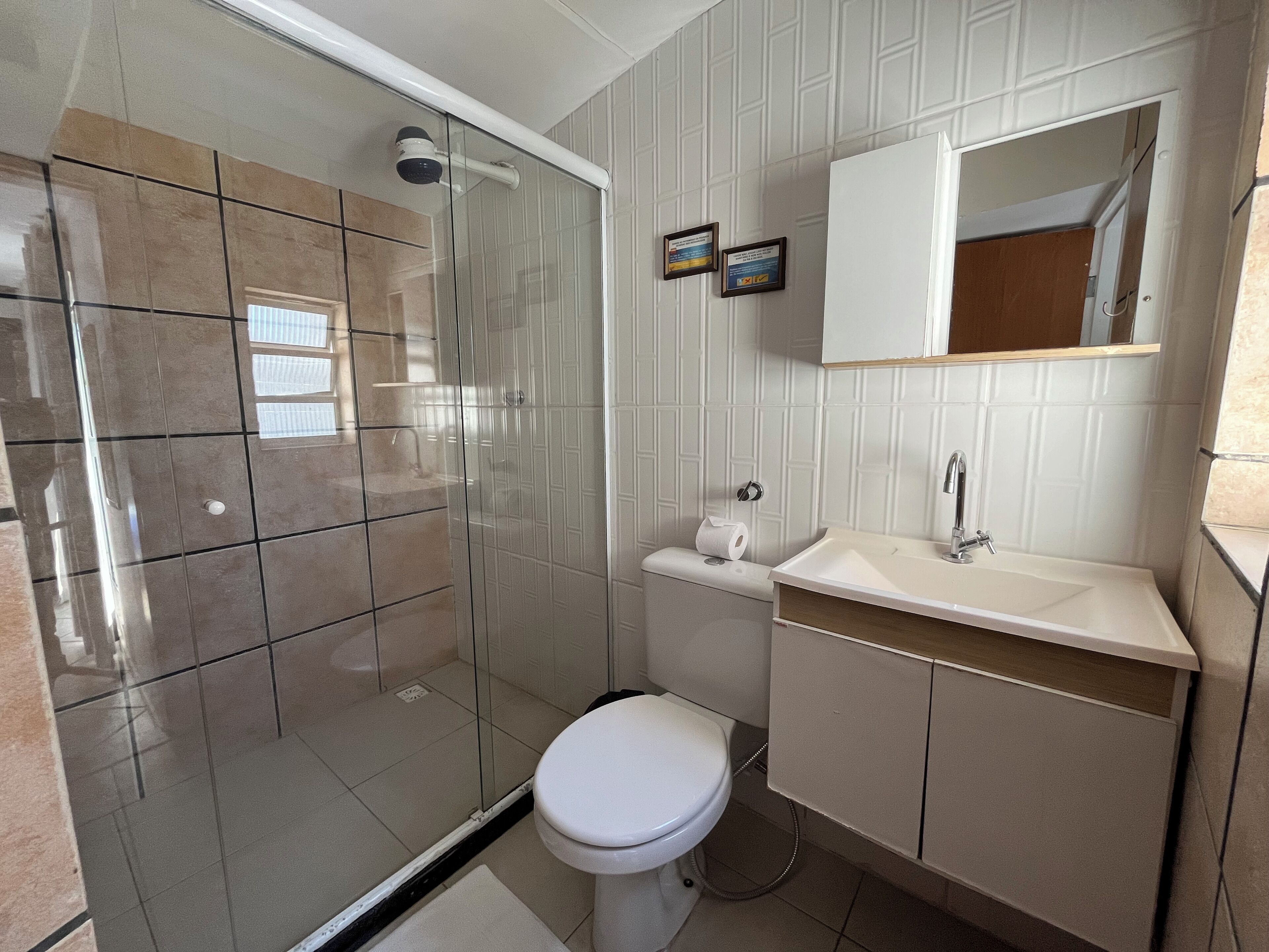 Uma casa de banho moderna com cabine de chuveiro em vidro, sanita, lavatório e espelho.