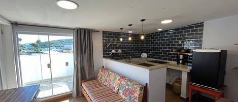 A modern kitchen with a central island, a sofa with a floral cover, and a dining table.