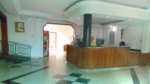 A lobby with a reception desk, a staircase, and a tiled floor. - Alvorada Palace Hotel (Cuiabá)
