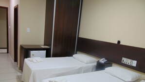 A hotel room with two single beds, a desk with a telephone, and a small refrigerator. - Alvorada Palace Hotel (Cuiabá)
