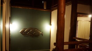 Ett rum med en grön vägg, en trästol och en fiskstaty.