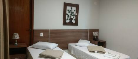 A hotel room with two single beds, a wooden headboard, a wall-mounted picture, and bedside lamps.