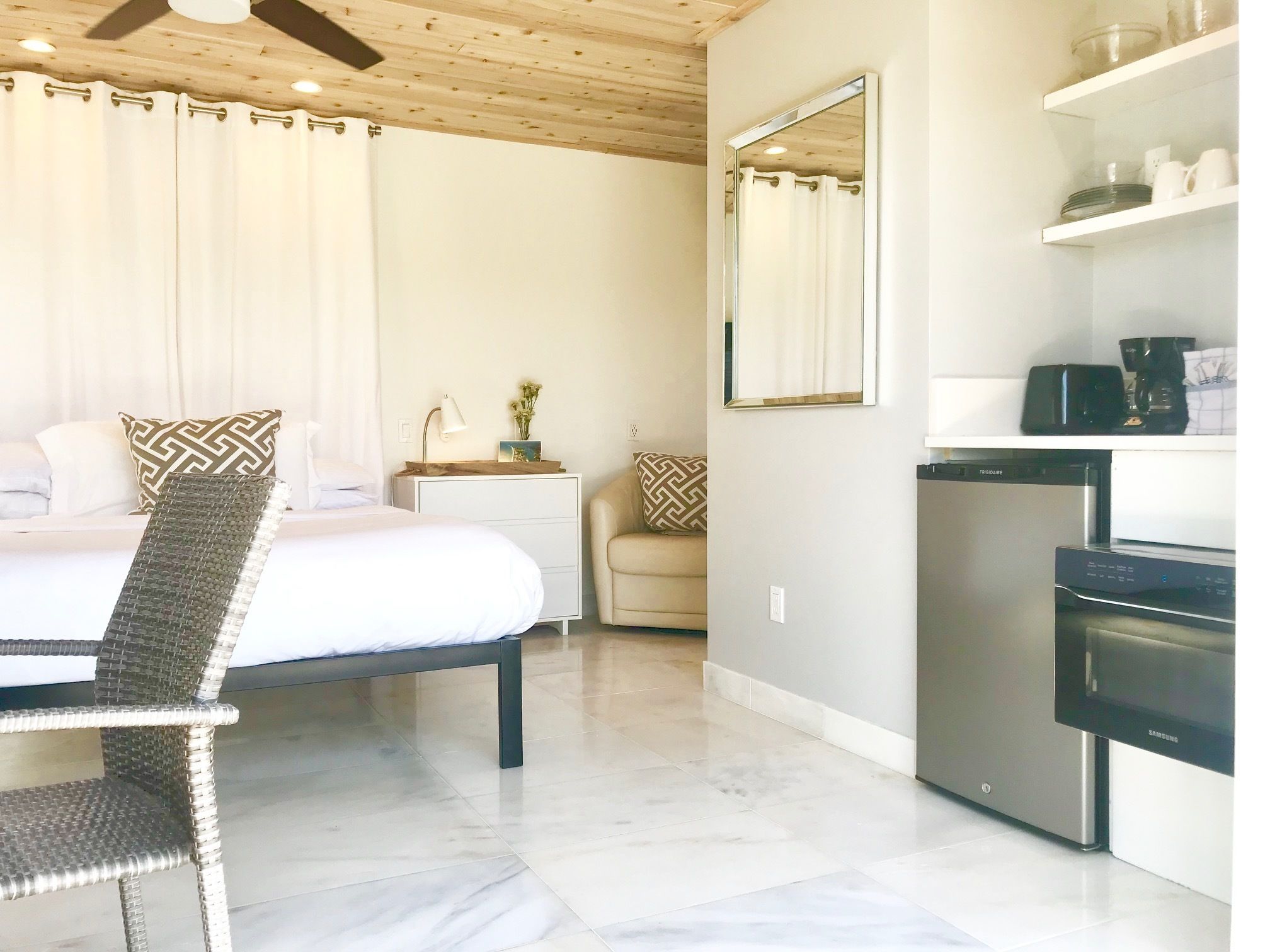 A bedroom with a bed, bedside table, lamp, and a chair.