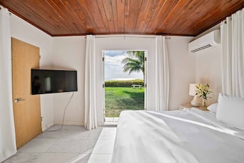 A modern kitchen with a refrigerator, a dining area with a table and chairs, and a view through a glass door to an outdoor area with a palm tree. at Casey Key Resort 
