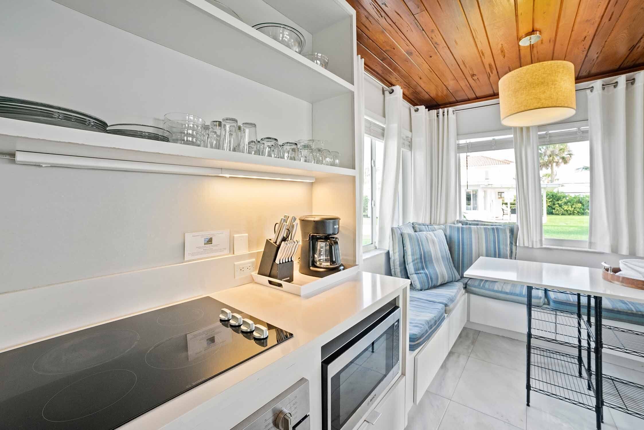 Una cocina moderna con horno empotrado, cafetera y comedor con banco y mesa.
