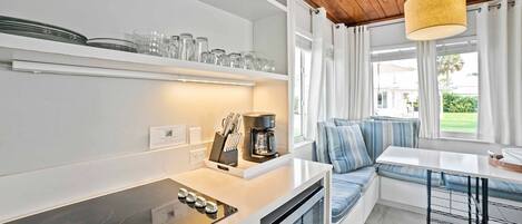 Una cocina moderna con horno empotrado, cafetera y comedor con banco y mesa.