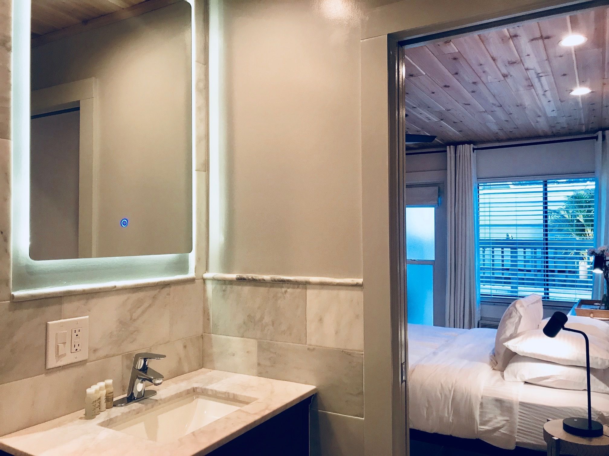 A bathroom with a large mirror, a sink, and a window.